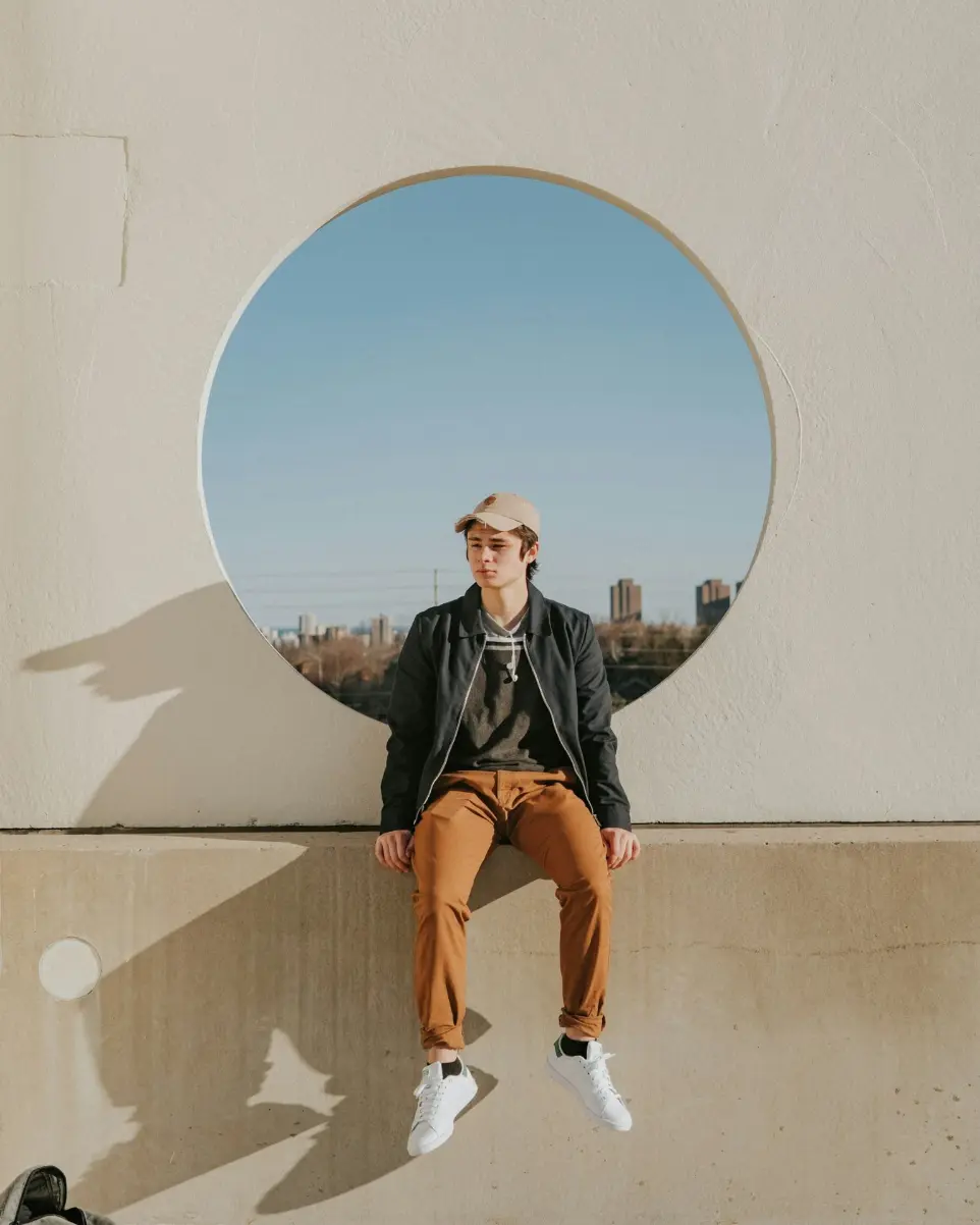 man sitting on gray concrete wall